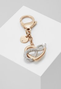 Charm in metallo color oro rosa con simbolo di infinito, decorato con cristalli trasparenti. Include un moschettone e una piccola etichetta incisa.