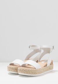 Sandales à talons blancs avec des détails en jute de style espadrille, design à bout ouvert, bride de cheville ajustable et dessus en synthétique lisse.