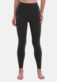 Zwarte high-waisted leggings van een soepele, rekbare stof met twee zijzakken en vlakke naden voor comfort en een gestroomlijnde pasvorm.