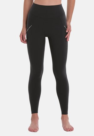 Schwarze hochtaillierte Leggings aus glattem, dehnbarem Stoff mit zwei Seitentaschen und flachen Nähten für Komfort und eine schlankere Passform.