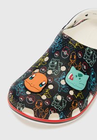 Black crocs featuring colorful Pokémon characters and icons. The design includes cut-out holes and a contrasting red accent on the sole.