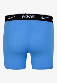 Nike zili zili bokseru apakšbikses ar melnu elastīgu jostu, uz kuras redzams balts logotipa teksts. Gluda auduma, pielāgota forma, bezšuvju dizains, minimālais šuvju skaits.