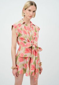 Abito con stampa floreale in rosa e verde, caratterizzato da un design senza maniche, chiusura frontale con bottoni, cintura in vita e gonna a due strati. Tessuto leggero e testurizzato.