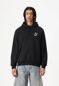 Black hoodie with a front pocket, adjustable drawstring hood, and white graphic detailing on the chest. Fabric appears soft and relaxed.