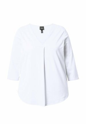 Valkea V-kaula-aukkoinen paita, jossa on 3/4-hihat ja keskellä etuosassa laskoskangas, esillä yksivärisellä taustalla.