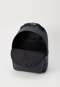 Černý batoh s šedým vzorovaným exteriérem. Obsahuje hlavní zipovou kapsu a přední kapsu s klopou. Texturovaná tkanina a robustní madla.