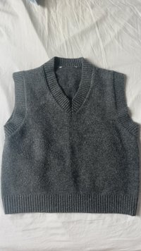 Grau ärmelloser Strickpullover mit V-Ausschnitt, mit gerippten Kanten und einer weichen, strukturierten Oberfläche. Gleichmäßig gestrickter Stoff ohne Muster.
