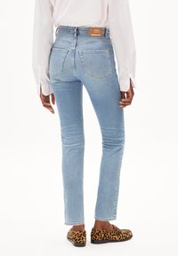 Light blue denim jeans with a high waist, straight legs, and back pockets. The outfit is complemented by leopard print shoes.