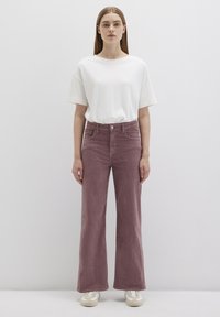 Loose-fit, ribbed corduroy pants in dusty rose color with a high waist and front pockets, paired with a plain white short-sleeve T-shirt.