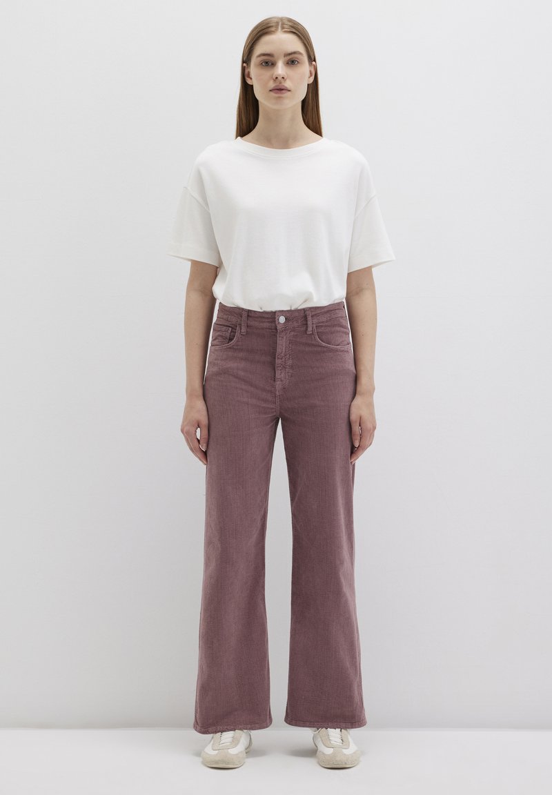 Loose-fit, ribbed corduroy pants in dusty rose color with a high waist and front pockets, paired with a plain white short-sleeve T-shirt.