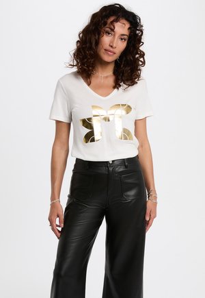 White v-neck t-shirt featuring a large gold metallic butterfly graphic. Paired with high-waisted black faux leather wide-leg pants.