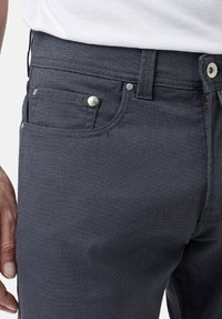 Jeans gris foncé en tissu texturé, avec une taille standard, des poches avant et des accents de boutons métalliques. Design classique à cinq poches.