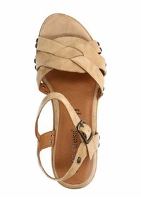 Beige suède sandaal met gekruiste banden, verstelbare enkelband en een bruine binnenzool. Kenmerkt zich door zwarte decoratieve kralen langs de zijkant.