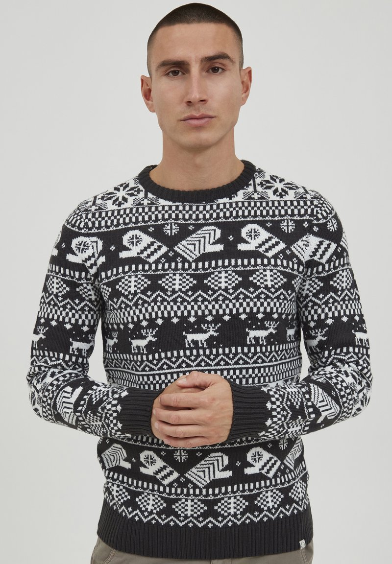 Gestrickter Pullover in Schwarz und Weiß mit einem Muster aus Schneeflocken, Rentieren und geometrischen Formen. Gerippter Halsausschnitt und Bündchen.