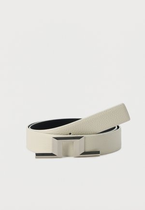 Δερμάτινη ζώνη σε ανοιχτό μπεζ με υφή, με ασημένια γεωμετρική μεταλλική αγκράφα, τυλιγμένη σε λευκό φόντο.