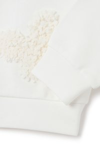 Sudadera blanca con detalle de aplique floral texturizado en el pecho y puños acanalados, hecha de suave tela de algodón.