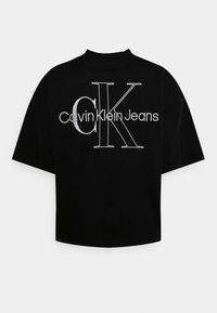 Svartkortärmad t-shirt i bomull. Har en stor vit "CK"-logotyp och texten "Calvin Klein Jeans" på baksidan. Rund halsdesign.