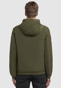 Olivgrüne, leichte Jacke mit Kapuze, die über eine glatte Textur, elastische Bündchen und einen gesäumten Saum verfügt; Logo am Nacken.
