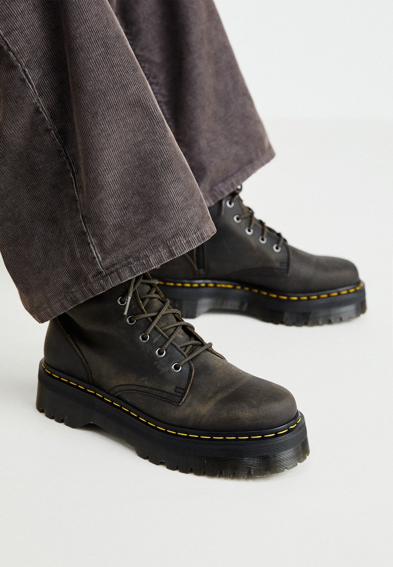 Svarte lærkampanser med gule sømmer, runde tær og tykke gummisåler. Snøring og teksturert materiale.