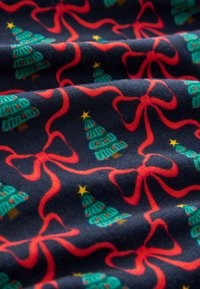 Tissu bleu marine avec un motif répétitif d'arbres de Noël verts et de nœuds rouges, rehaussé d'étoiles jaunes. Texture douce avec un tissage apparent.