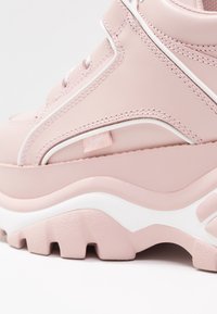 Rosa plattformssneaker i glansigt syntetmaterial med vita accenter, texturerad sula och framträdande varumärkesetikett. Har rund snörning och stickade detaljer.