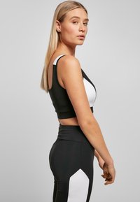 Crno-bijeli crop top s geometrijskim uzorkom, u kombinaciji s crnim tajicama visokog struka koje imaju bijeli dijamantasti naglasak.