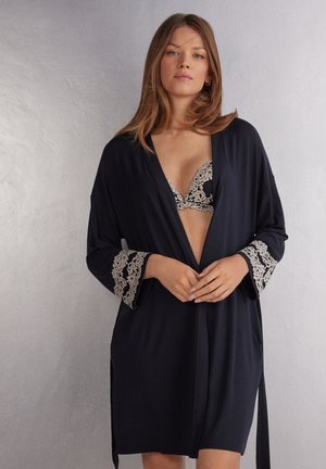 Robe di stile kimono nero con maniche ampie, caratterizzata da dettagli in pizzo beige all'orlo delle maniche e un design aperto. Tessuto morbido.