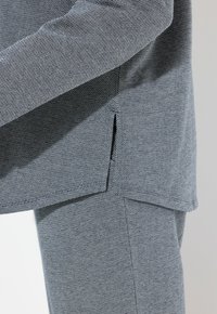 Top y fondo de tejido a rayas grises con aberturas laterales. El textil presenta una textura sutil y un diseño de corte relajado.