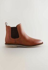 Stivale Chelsea in pelle marrone con pannelli laterali elasticizzati, punta tonda e suola texturizzata. Presenta un'apposita linguetta per facilitare l'indossamento.