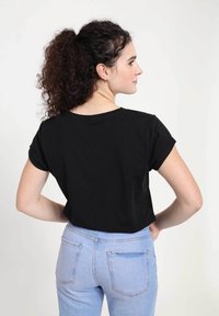 Camiseta corta de manga corta negra con escote redondo. Combinada con jeans ajustados de tiro alto en un azul claro, que cuentan con bolsillos traseros y un ajuste clásico.