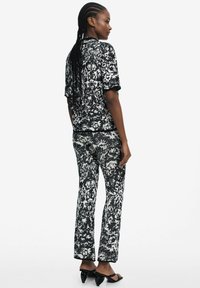 Black and white patterned co-ord set featuring a short-sleeve top and fitted pants, with a textured, woven fabric and contrasting trim.