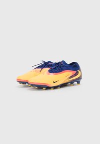 Orange and navy football boots with textured upper, contrasting red accents, and yellow studs, designed for firm ground surfaces.