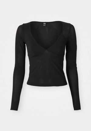Černý top s dlouhým rukávem s hlubokým výstřihem do V, vyrobený z měkké elastické látky a s vlněnými okraji na rukávech a spodním lemu.
