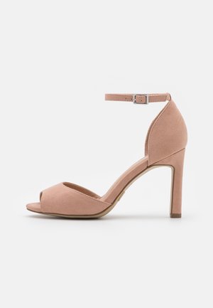 Sandale à talons hauts en suede rose avec un bout ouvert et une fine bride de cheville, présentant une texture lisse et un design de talon effilé.