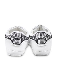 Witte sneakers met een gladde textuur, voorzien van een zwart-witte gestreepte ontwerp op de hak en een logo dat op de achterkant is gegraveerd.