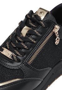 Scarpa sportiva nera con tomaia in tessuto testurizzato. Presenta dettagli dorati, lacci e una cerniera laterale. Suola solida con texture variabili.