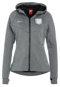 Chaqueta gris con cremallera, hecha de tejido suave, con capucha, logo de Nike y emblema en el pecho, con un diseño aerodinámico y acentos acanalados.