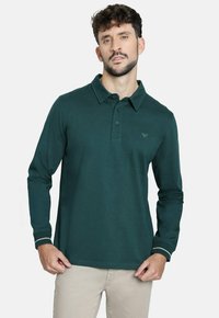Polo de manga larga en verde oscuro con cuello, tapeta de tres botones y un sutil detalle de logo. Presenta costuras en los puños en contraste.