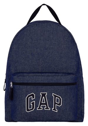 Sac à dos en denim bleu avec fermeture éclair noire et poignée noire, la poche avant affiche de grandes lettres blanches contourées formant GAP.