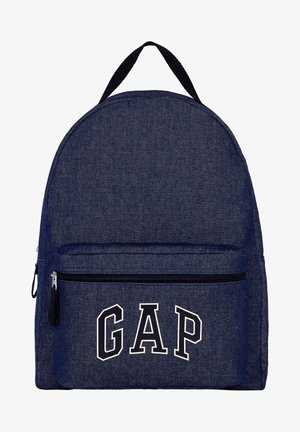 Blauwe denimrugzak met zwarte rits en zwart handvat, het voorvak toont grote witte omrande letters die GAP spellen.