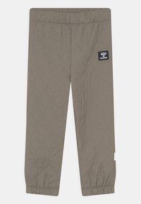 Gep quiltete, taupefarbene Hose mit elastischem Bund und gerafften Bündchen, die ein geometrisches Muster und einen Logo-Patch auf der linken Seite aufweist.