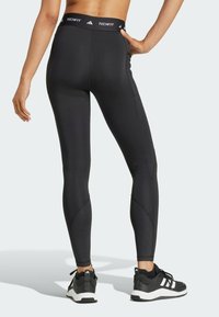 Leggins Techfit negros hechos de material elástico, con un diseño ajustado, paneles texturizados en las pantorrillas y una cintura elástica con branding.