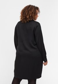 Vestito camicia nero a maniche lunghe con una texture liscia, polsini con bottoni, orlo dritto e colletto classico, che consente una vestibilità rilassata.