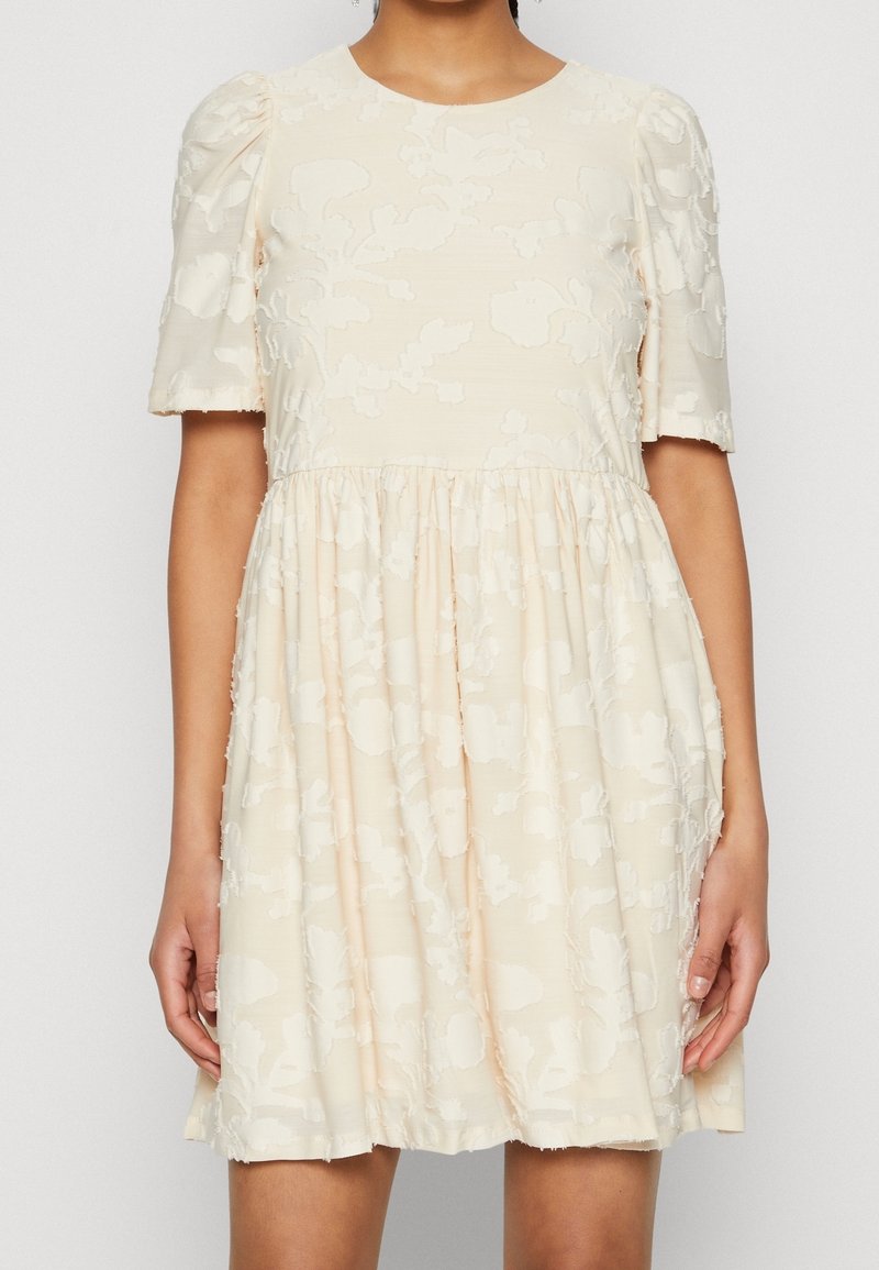 Kurzes Kleid mit puffähnlichen Ärmeln in hellbeige mit floralem Muster. Es hat ein tailliertes Oberteil und einen ausgestellten Rock. Leichter Stoff, runder Ausschnitt.