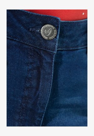 Donkerblauwe denim jeans met een vlakke voorkant, voorzien van een metalen knoop met logodetail en contrasterende stiksels langs de naden.