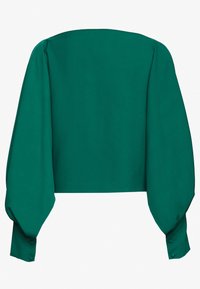 Blouse courte verte avec manches longues bouffantes, présentant une texture lisse et des boutons en accents sur les poignets. Vue de dos montrée.