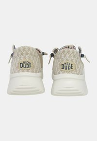 Baskets tissées beige avec un motif chevron, dotées d'une semelle en caoutchouc blanche et d'un écusson logo à l'arrière. Lacées avec des languettes ajustables.