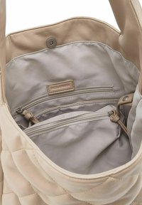 Beige gewatteerde handtas met glad leren buitenkant, voorzien van een beige stoffen voering, een ritssluiting aan de binnenkant en een drukknoopsluiting bovenaan.