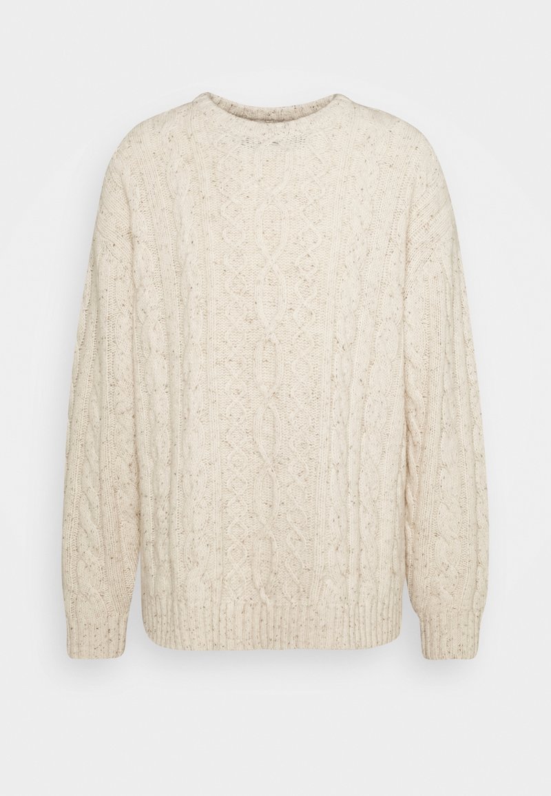 Krämfärgad stickad tröja med kabelstickat mönster, rund halsringning och ribbade avslut på ärmar och nederkant. Mjuk textur med en avslappnad passform.