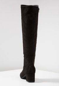 Botte noire en daim montant au-dessus du genou avec un bout rond, un talon carré et une fermeture éclair latérale. Texture lisse, tige ajustée et construction robuste.